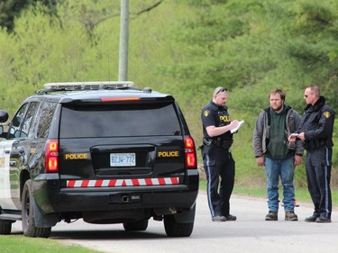 Ontario Provincial Police officers speak to a resident on Front Road, north of Vanastra, during an investigation into a suspicious death on Friday. (DALE CARRUTHERS / THE LONDON FREE PRESS)