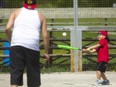 Oaklynd Hill, 5, takes a swing at a pitch thrown by his dad Wilfred Lowe as they practice baseball in Vauxhall Park in London, Ont. on Sunday May 13, 2018.   (MIKE HENSEN, The London Free Press)