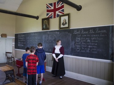 Christina Kaszuba plays the part of Miss Kay, teaching the words of God Save The Queen to children at the school house in Fanshawe Pioneer Village on Victoria Day. Derek Ruttan/The London Free Press/Postmedia Network