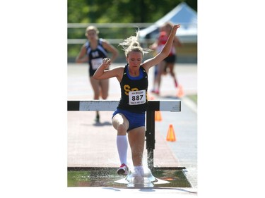 Mikenna Vanderheyden of Strathroy DCI lands in the water pit on the second lap of the girls 1500m steeplechase at TD stadium in London on Thursday, the first day of the WOSSAA track and field meet. Vanderheyden, who owns the OFSAA record of 4:46.54 set last year, won the event solo.  Mike Hensen/The London Free Press