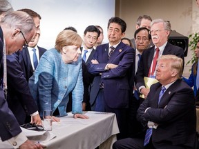 This photo released on Twitter by the German government on Saturday shows U.S, President Donald Trump, right, talking with German Chancellor Angela Merkel, centre, and surrounded by other G7 leaders during a meeting of the G7 summit in La Malbaie, Que,. (AFP Photo/Bundesregierung/Jesco DENZEL)