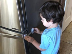 Three-year-old Imran Sethna examines a child safety latch on the refrigerator door. Baby-proofing products have become more diversified in recent years.