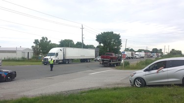 A Chatham-Kent police officer directs traffic backed up on Queen's Line, on the east side of Tilbury, while both the eastbound and westbound lanes of Highway 401 remain closed following a collision between two tractor-trailers Friday morning that has left one man dead. (Ellwood Shreve/Postmedia Network)