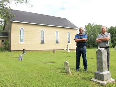 David Middleton, left, and Bryan Prince stand in the cemetery of the North Buxton Community Church in North Buxton on Tuesday. The congregation has been ordered by the British Methodist Episcopal Church of Canada to vacate the church, cemetery and community hall. Ellwood Shreve/Postmedia Network