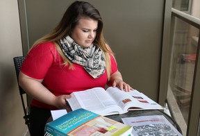 Dental hygiene student Merisa Buragina reviews one of her textbooks on her apartment's balcony. Buragina will graduate from her program on June 7. (SHANNON COULTER, The London Free Press)