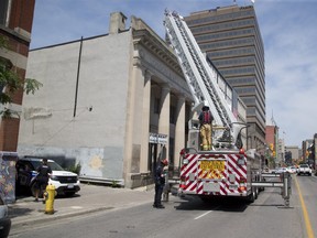 A London firefighter descends from a ladder truck Sunday after police called in the fire department to retrieve evidence of a crime from the rooftop of the historic former London and Western Trusts building on Richmond Street near York Street.