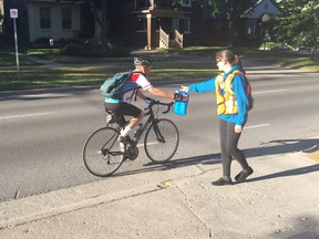 Transportation demand management coordinator Allison Miller hands off a swag bag to a cyclist on Queens Avenue Monday morning to kick off London Celebrates Cycling week.