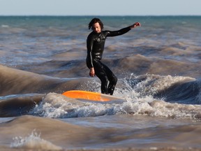 A surfer rides a wave at Port Stanley’s main beach last Wednesday.  (DALE CARRUTHERS, The London Free Press)
