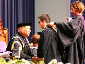 Western University chancellor Jack Cowin, left, speaks with bachelor of medical sciences graduate John Antonio Chmiel while Dr. Sarah McLean places a hood over his shoulders during Western's 311th convocation ceremony on Thursday, June 14, 2018. (DALE CARRUTHERS, The London Free Press)