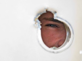 A witness says a man was shot in the wrist after an intruder gained entry by shooting the door handle off the back door of Unit 47 at 1443 Huron St. in London on Wednesday. Resident Gordie Magee peers through the hole left in his back door. Derek Ruttan/The London Free Press