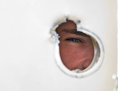 A witness says a man was shot in the wrist after an intruder gained entry by shooting the door handle off the back door of Unit 47 at 1443 Huron St. in London. Resident Gordie Magee peers through the hole left in his back door. Photo taken on June 6, 2018. Derek Ruttan/The London Free Press