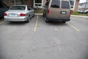 Blood stains the parking area in front of unit 47 at 1443 Huron Street.  A man was shot in the hand/wrist with a shotgun after an intruder gained entry by shooting the door handle off the back door. (Derek Ruttan/The London Free Press)