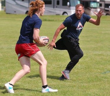 Collin Smibert runs the ball as Rob McQueen, an assistant coach for the Medway Cowboys,  teaches positional play that uses the sidelines as an extra defender during practice Wednesday at the St. George's rugby fields in London. The Cowboys are hosting this year's provincial championship featuring the best teams from across Ontario, and the Cowboys are ranked No. 1 coming in. Mike Hensen/The London Free Press