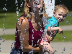 Vanessa Mahon took her daughter Emmeline, 17 months, to the splash pad in Gibbons Park but seemed to be having as much fun herself as she tries for a sip of water in this Free Press file photo (Mike Hensen/The London Free Press)