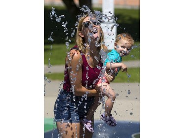 Vanessa Mahon took her daughter Emmeline, 17 months, to the splash pad in Gibbons Park but seemed to be having as much fun herself as she tries for a sip of water, while cooling off from the already warm Friday morning in London.  Mahon said the splash pad "is our favorite way to get out of the heat, no place we'd rather go." (Mike Hensen/The London Free Press)