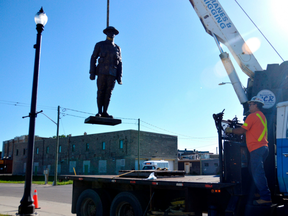 Tim Russell hoists the Great War memorial statue onto a skid Monday morning in St. Thomas. The memorial will be refurbished this week, one of the final touches to the $280,000 memorial garden project on Moore Street. (Louis Pin/Postmedia)