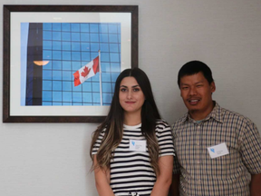 Delveen Al-Naamo (left) and Yam Gurung pose beside a picture of a Canadian flag at the Four Points hotel on Wellington Road South. Both Al-Naamo and Gurung spoke on a refugee panel at the Life as a Refugee conference, organized by the London Cross Cultural Learner Centre, on Wednesday. (Shannon Coulter / The London Free Press).