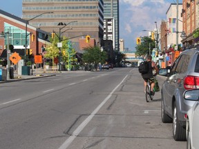 A cyclist rides around parked cars next to the bicycle lane at King and Talbot Streets. (SHALU MEHTA/THE LONDON FREE PRESS)