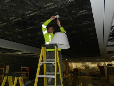 Vince Surmanski installs a new lighting fixture in the ground floor restaurant that will be part of the new downtown campus of Fanshawe College and serve as a training ground for students of the culinary program. Tin ceiling tiles from the original Kingsmill's department store were refurbished and installed in the restaurant. Hank Daniszewsk /The London Free Press
