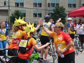 Cyclists high-five after crossing the finish line at the PwC MS Bike Tour Saturday afternoon.
