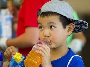 Kingsley Huang, 7, of London was busy hydrating and cooling off at East Park with a drink and grabbing a popsicle during a break in his golf lessons. Photograph taken on Tuesday July 3, 2018.  Mike Hensen/The London Free Press/Postmedia Network
