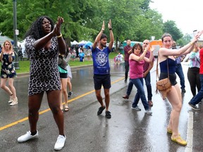 Naomi Nadea leads the street dancing as Samba Squad performs during their traditional Sunfest kickoff concert on the Wellington Street stage on Thursday July 5, 2018.  The rain kept the numbers down early in the set. Mike Hensen/The London Free Press/Postmedia Network ORG XMIT: POS1807051746110113