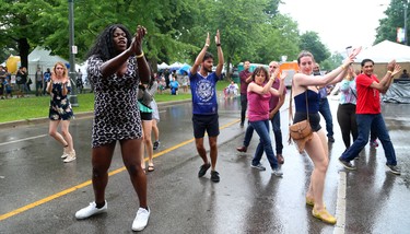 Naomi Nadea leads the street dancing as Samba Squad performs during their traditional Sunfest kickoff concert on the Wellington Street stage on Thursday July 5, 2018.  The rain kept the numbers down early in the set. (Mike Hensen/The London Free Press)