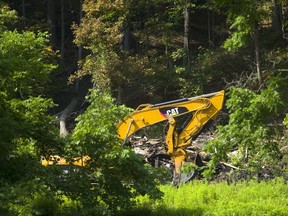 A large excavator sits in front of a pile of debris where once a large home stood called the Cedars, on Riverside Drive just below Springbank Dam in London, Ont. It was destroyed by a fire Saturday night. Photograph taken on Monday July 9, 2018.