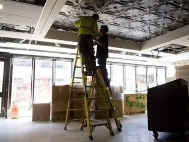 Vince Surmanski and Jeremy Standish install a light in the new restaurant being built in the Fanshawe College building on Dundas Street in London.  The Chef's Table at Fanshawe College will feature a restored tin roof from Kingsmill's as well as a bare brick wall from the store. Mike Hensen/The London Free Press/Postmedia Network