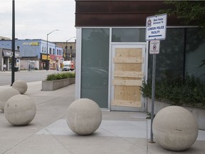 A door to London police headquarters on Dundas Street at Adelaide Street is boarded up Thursday. A man was arrested for allegedly breaking the glass door Wednesday evening. (Derek Ruttan/The London Free Press)