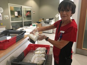 Donor care associate Julie Baines holds a new donation of whole blood before placing it on a cooling tray at the Canadian Blood Services clinic on Wharncliffe Rd. S. Recent blood donations are kept on the cooling tray until the evening, when they are transported to Brampton to be distributed. (SHANNON COULTER, The London Free Press)