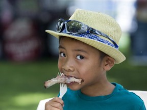 Six-year-old Kevin Cao puts pork on his fork during his first ever London Ribfest in London, Ont. on Friday August 3, 2018.  He was lunching with his father Owen, sister Cindy, brother Tommy and mother Mai Vu. "It's so tasty," the youngster exclaimed. Derek Ruttan/The London Free Press/Postmedia Network