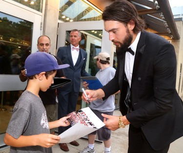 Drew Doughty signs a photo for Andrew Theologos, 9 as he arrives for Logan Couture's All in for Brain Research charity casino night at Centennial Hall in London Thursday.  Mike Hensen/The London Free Press/Postmedia Network