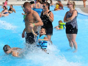 Ryan Grant of London helps his daughter Sommer, 3, avoid a breaking wave in East Park's giant wave pool on Tuesday. The water park was nearly filled by local residents seeking relief from the heat and humidity. (Mike Hensen/The London Free Press)