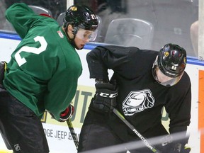 Defenceman Adam Boqvist, in green, tries to dig the puck out between the feet of Sahil Panwar during a Knights rookie squad game at Budweiser Gardens Wednesday.  (Mike Hensen/The London Free Press)