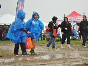 Guests of the International Plowing Match & Rural Expo on Day 3 walk through muddy conditions in the rain at the Tented City in Chatham-Kent Sept. 20, 2018. The Tented City was closed in the afternoon.