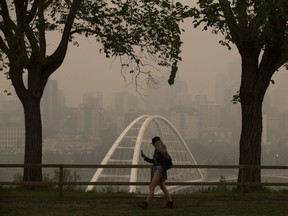 A pedestrian takes photos of the smokey Edmonton skyline last month as smoke from forest fires in British Columbia blanketed the Edmonton region (David Bloom/Postmedia News)