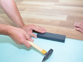 Contractors installing wooden laminate flooring with insulation and soundproofing sheets. (Getty Images)