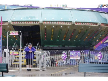 A ride operator looks around for business as a rainy Monday afternoon made for lonely midway at the Western Fair in London on Monday. (Derek Ruttan/The London Free Press)