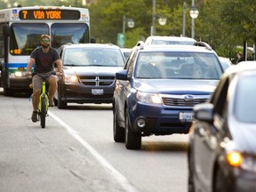 Ben Cowie, owner of the London Bicycle Cafe on Adelaide Street cycles down King Street while having to keep an eye on cars and buses that cross into the bike lane. (Mike Hensen/The London Free Press)