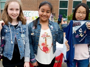 Students Pauline Boers, left, Khrystel Libag, and Chaehyun Min display the upcycled bags and denim patches they were selling at a social enterprise flea market at Masonville public school during the last school year. The students donated proceeds to Green Action. (Postmedia file photo)