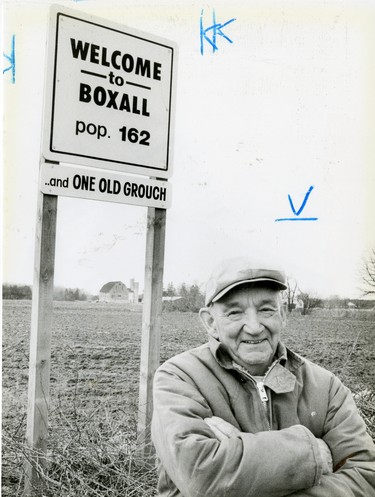 Mason Fulkerson a retired farmer who lives at RR 1, Port Stanley stands in front of the Boxall welcome sign, 1988. (London Free Press files)