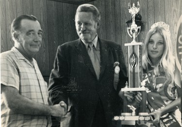 Vicky Peterson, Queen of the Port Stanley festival presents a trophy to winner of the fish-tug parade to Captain Norman MacIver, left. Chamber of Commerce board of directors chairman Gordon Hubbard looks on, 1972.  (London Free Press files)