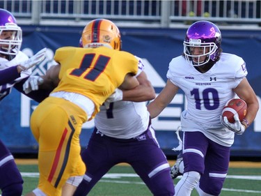 Western Mustangs Mike Saneness runs back a punt as Queen's Golden Gaels Louis Hebert looks to make the tackle during their Ontario University Athletics football game in Kingston Saturday Sept. 9 2018. Western won 26-23.   Ian MacAlpine/Postmedia Network