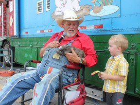 Ken LaSalle from "Boss Hogs Celebrity Racing Pigs and Ducks" shows off a racing pig named Dottie (racing name Bacon Barny) to Lucas Johnston-Scafe during the final day of the Western Fair on Sunday, Sept. 16, 2018. (MEGAN STACEY/The London Free Press)