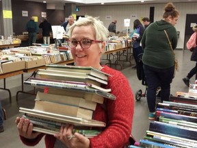 Londoner Lisa Gaverluk hefts some of the more than 20 books she found to buy at the annual Friends of the London Public Library sale on Friday in the basement of Centennial Hall. The sale continues Saturday and Sunday. (DAN BROWN, The London Free Press)