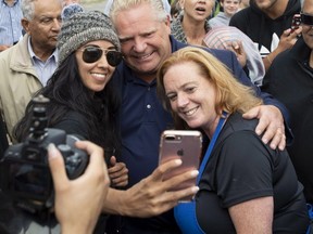 Ontario Premier Doug Ford and cabinet minister Lisa MacLeod (right) take selfies with people gathered at Larkin House Community Centre on Sept. 23, 2018. (The Canadian Press)