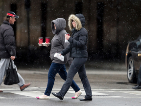 Pedestrians brave a mix of rain and flurries as they cross London's King Street. (File photo)