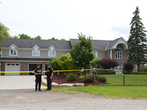 OPP officers look over notes outside a Westminster Drive home, where they were investigating the death of Robert St. Denis, 51, in June 2015. (File photo)