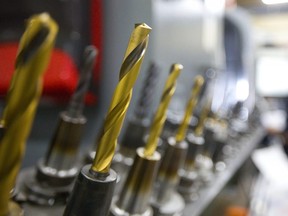 Various cutting and drilling bits are lined up as Cameron Milne works programming a computer numerical control (CNC) mill at Armo Tool near Delaware. (Mike Hensen/The London Free Press)